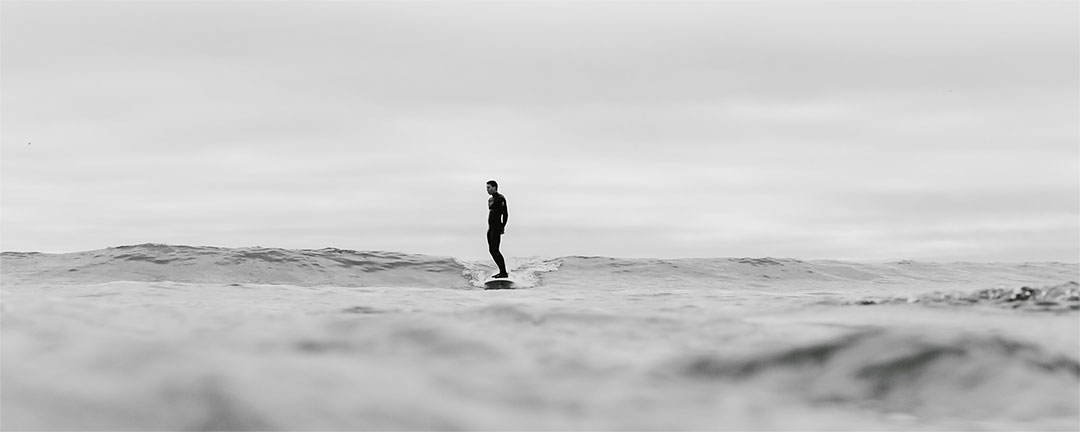 surfista de longboard en playa de Salinas mientras esta de ruta camper por el norte